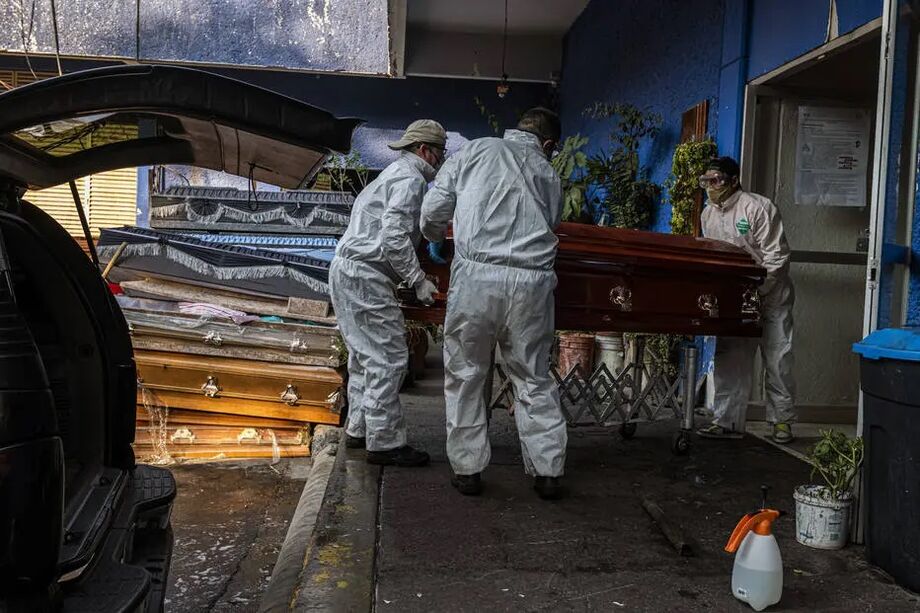 Trabalhadores carregam caixão de vítima da covid-19 para ser cremado em cemitério da Cidade do México, onde em alguns hospitais os pacientes ficam dias deitados no chão