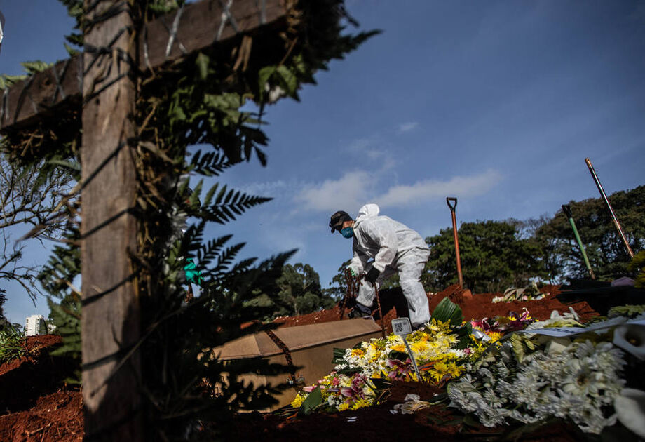 Funcionários vestidos com roupas de proteção fazem o sepultamento de vítimas do novo coronavírus no Cemitério da Vila Formosa, na zona leste da capital paulista