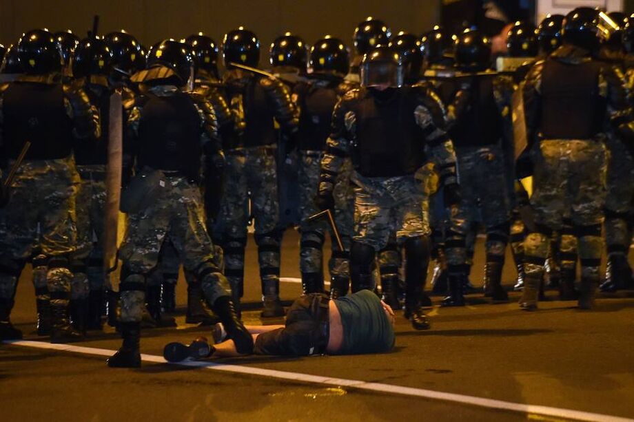 Barreira policial passa por homem caído no chão durante protestos da oposição na Bielo-Rússia