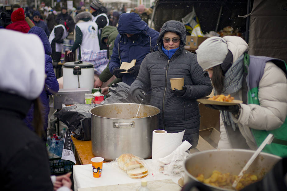 Voluntários servem comida quente para refugiados que fogem do conflito da vizinha Ucrânia na fronteira romeno-ucraniana.