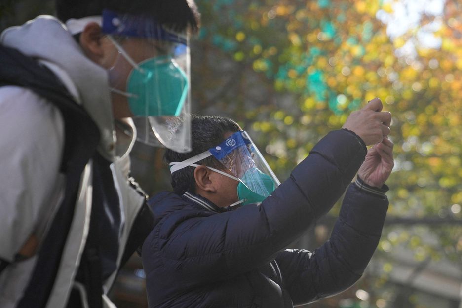 Homens usam máscaras e face shields ao chegar em hospital de Xangai.