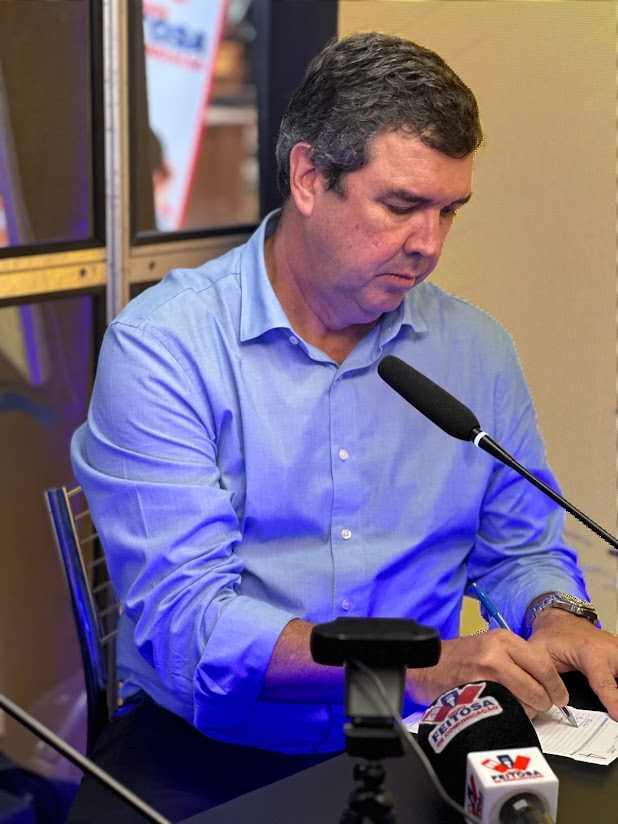 escrever 10 opções de legenda de uma foto  onde aparece o presidente da acrissul guilherme bumlai, governardo eduardo riedel, e o radialista Marcos Rondon e o jornalista Carlos Ferreira durrante entrevista exclusiva ao grupo feitosa de comunicação