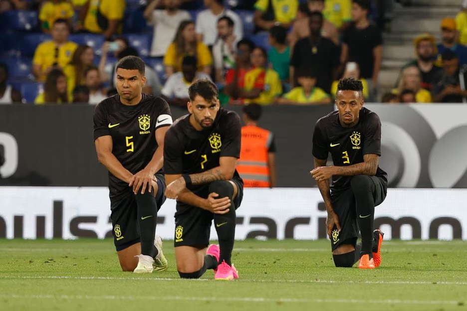 Jogadores brasileiros ajoelhados antes de a bola rolar em Barcelona. 