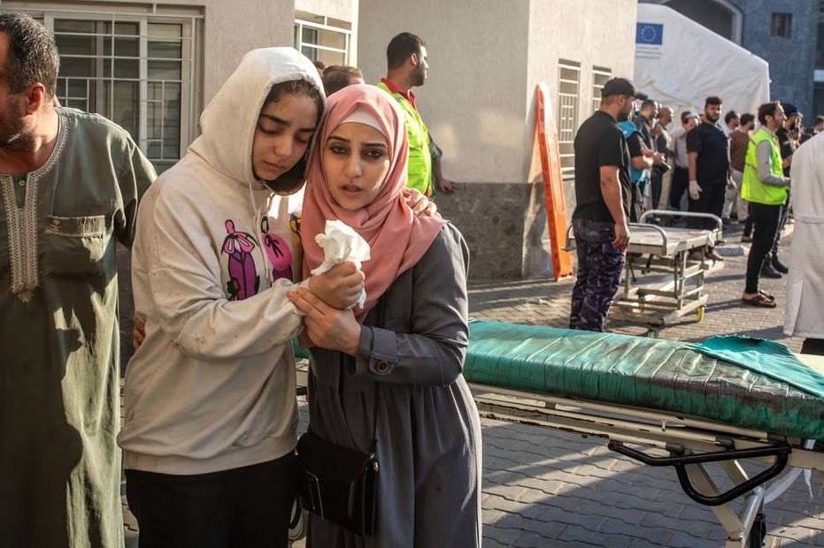 Duas jovens se agarram uma à outra para se apoiar no Hospital Al-Shifa, na Cidade de Gaza, após ataques aéreos israelenses na quinta-feira, 12 de outubro de 2023