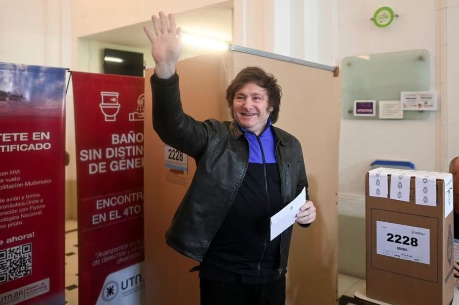 Milei acena para jornalistas antes de depositar seu voto em um colégio do bairro de Palermo, em Buenos Aires