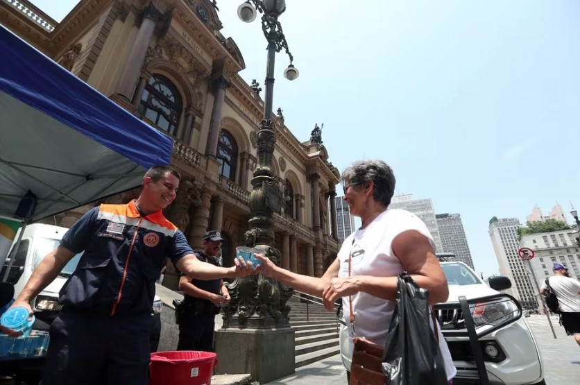 Agentes da Defesa distribuem água para pedestres em frente ao Theatro Municipal, no centro de São Paulo 