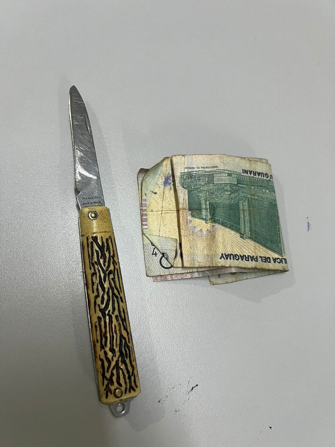 O canivete e a quantia em dinheiro apreendidos com o detido