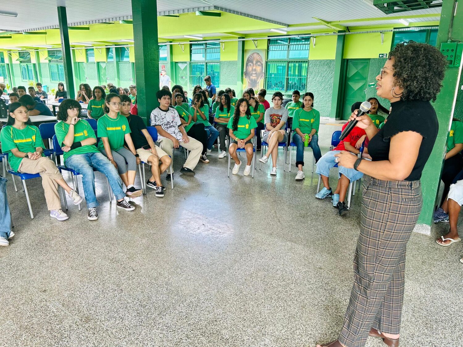 No pátio da escola, a técnica da Subsecretaria de Políticas Públicas para a Promoção da Igualdade Racial, Irineia Cesário, conversa com os alunos
