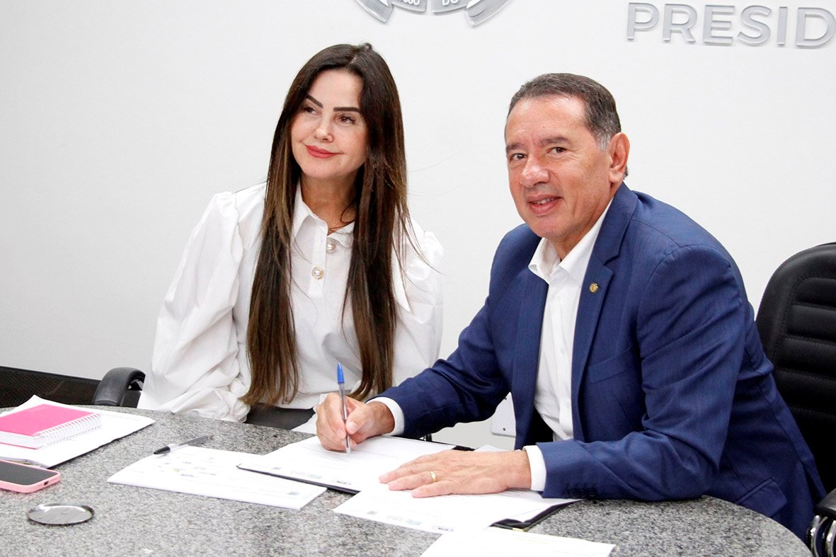 Deputado Gerson Claro, ao lado de Mara Caseiro, assina o termo