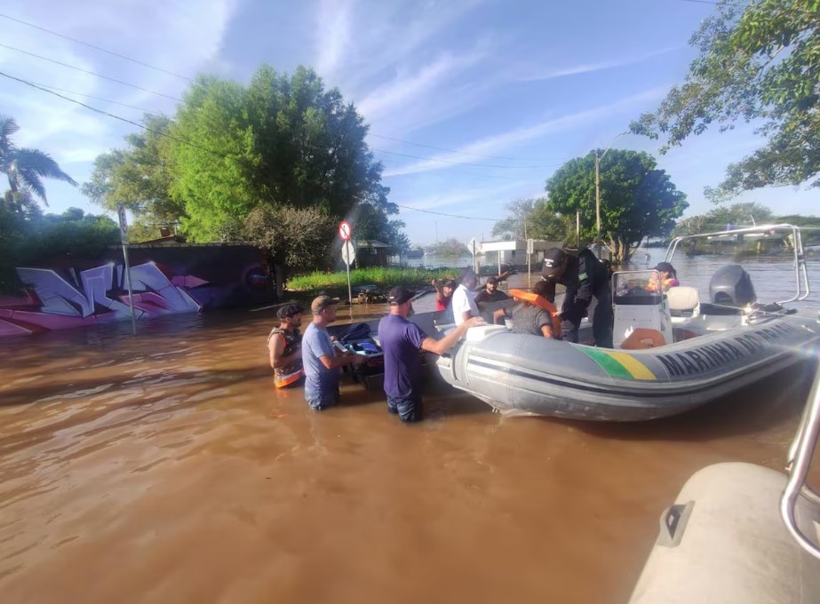 População em áreas totalmente tomadas pelas águas sendo resgatadas