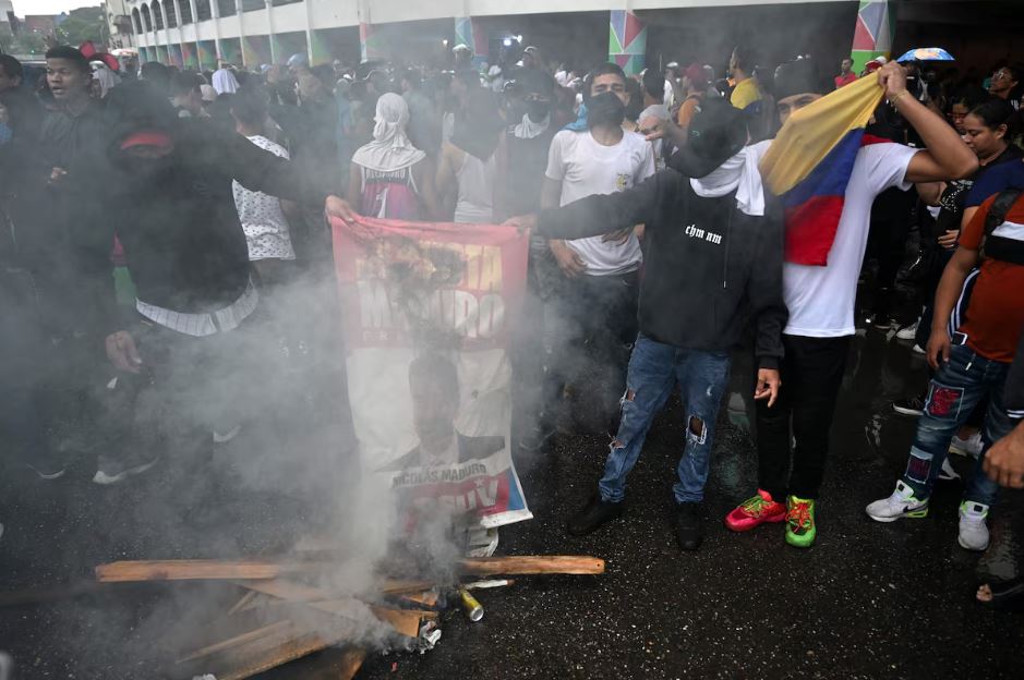 Oponentes do ditador Nicolás Maduro queimam uma baideira do chavista no bairro Petare, Caracas