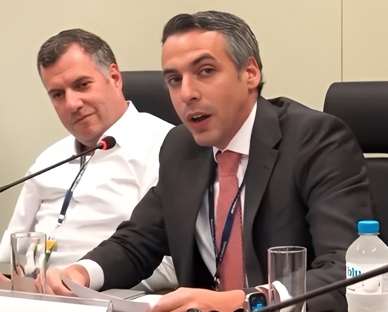 : João Pedro Palhano Melke, o cérebro jurídico por trás do acordo bilionário, acompanha atentamente. Ao fundo, seu irmão, Carlos Melke, encara o futuro da Ulbra, sabendo que a assinatura marca apenas o começo da recuperação.