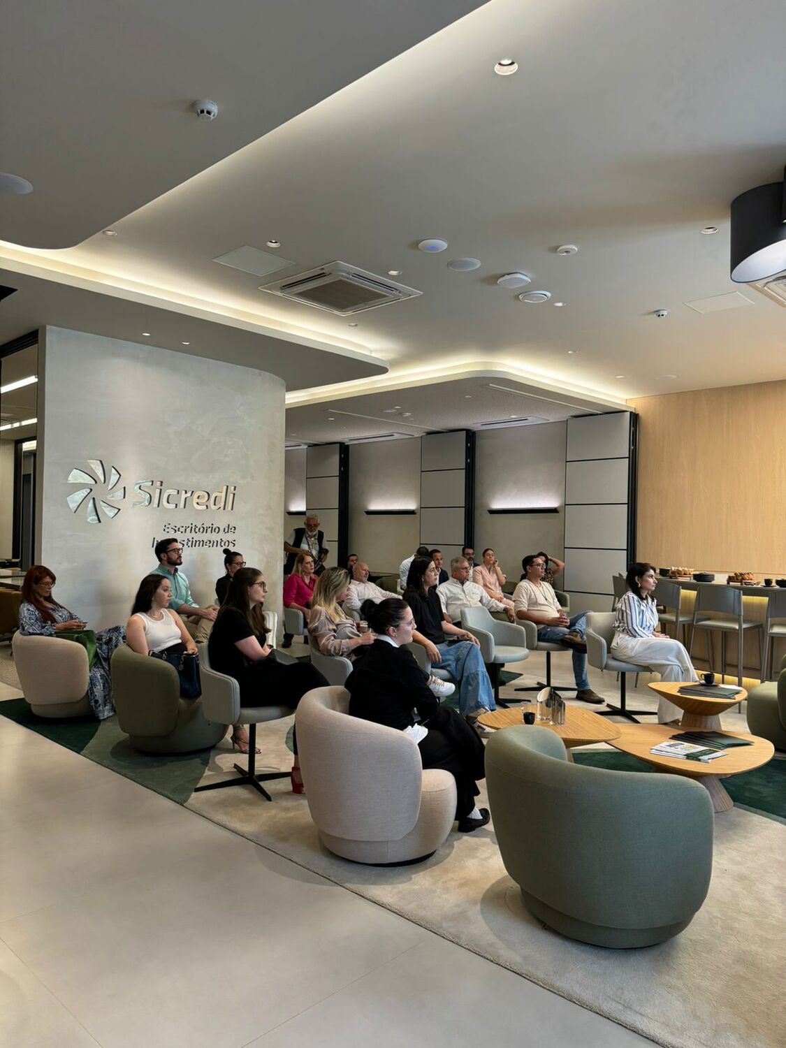 Participantes reunidos no escritório de investimentos do Sicredi para uma palestra sobre finanças com a educadora Sabrina Nakao