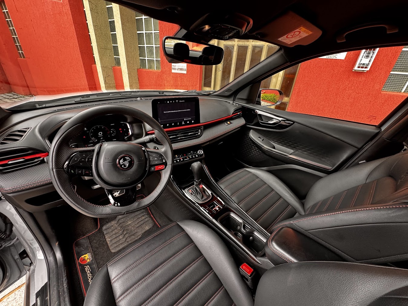 Interior do Fiat Fastback Abarth revela detalhes sofisticados, com acabamento premium, costuras vermelhas e pedaleiras esportivas em alumínio