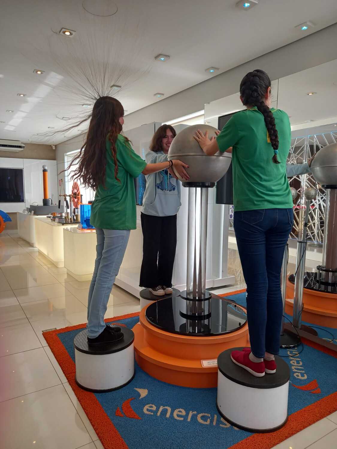 Estudantes se divertem em um gerador de Van de Graaff