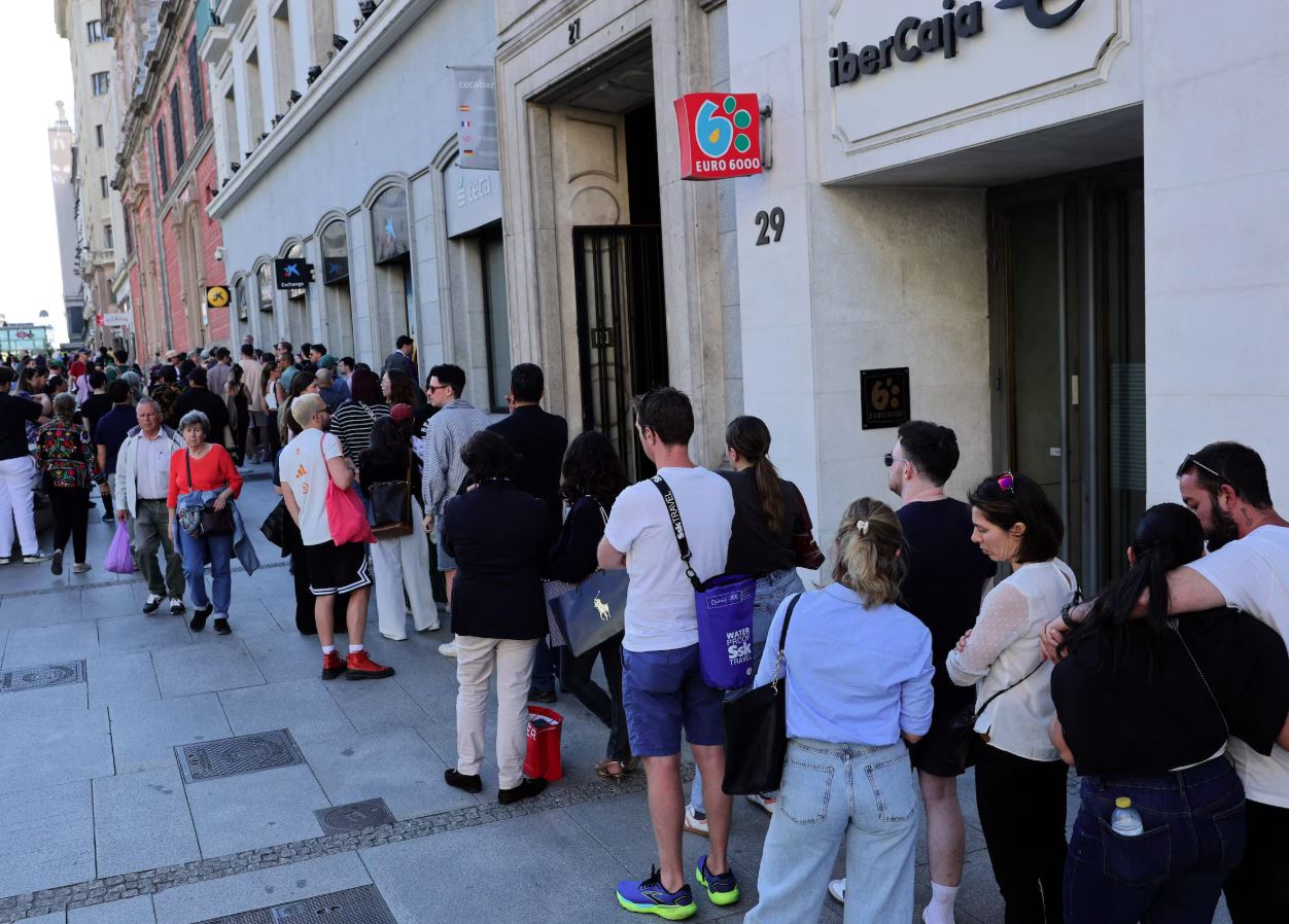 Pessoas fazem fila para tentar sacar dinheiro em um caixa eletrônico, já que o pagamento com cartão de crédito não está disponível devido a uma grande queda de energia na Espanha, em Madri