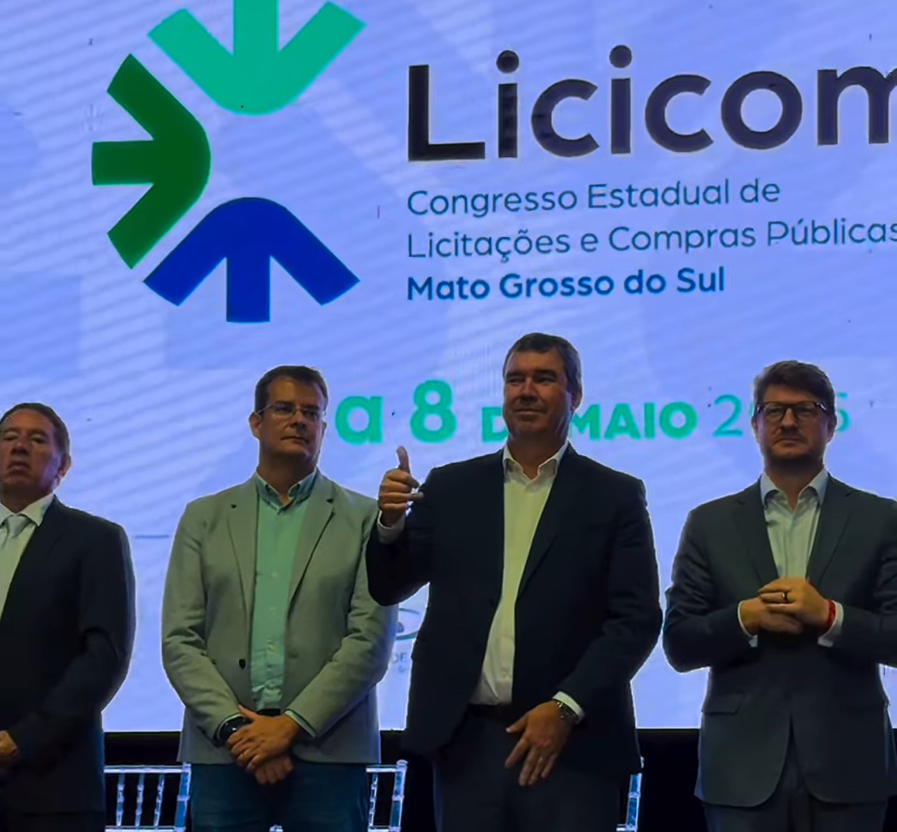 Governador Eduardo Riedel (PSDB) faz sinal de positivo ao lado de secretários estaduais na abertura do Licicomp 2025, em Campo Grande.