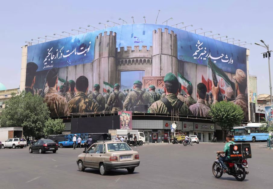 Iranianos passam por um cartaz anti-Israel na Praça Enghlab, em Teerã, em 14 de junho de 2025: exército de Israel disse que seus caças estavam prontos para retomar os ataques a alvos em Teerã