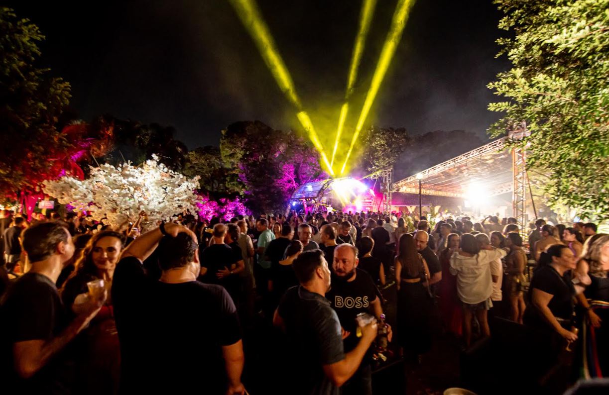 Ambiente ao ar livre, com natureza e luzes cênicas, cria o cenário perfeito para a festa que une arte e liberdade.