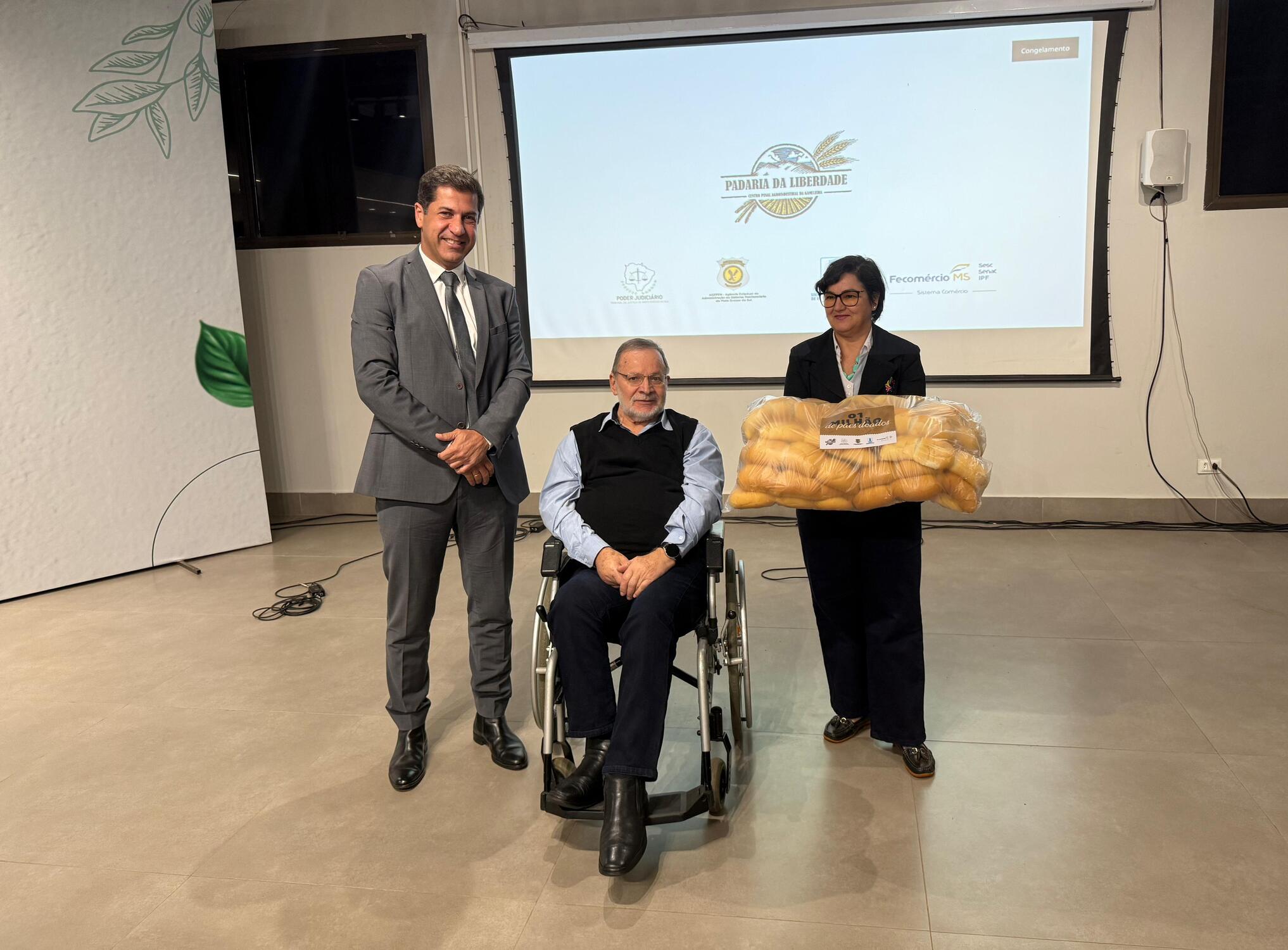 Albino Coimbra Neto, Vitor Mello e representante de entidade social participam da entrega simbólica dos pães da Padaria da Liberdade.