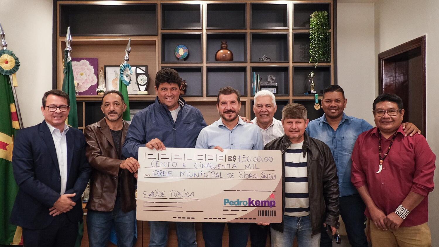 Deputado Pedro Kemp entrega simbolicamente cheque de R$ 150 mil ao lado do prefeito Rodrigo Basso e lideranças de Sidrolândia para investimentos em saúde pública.