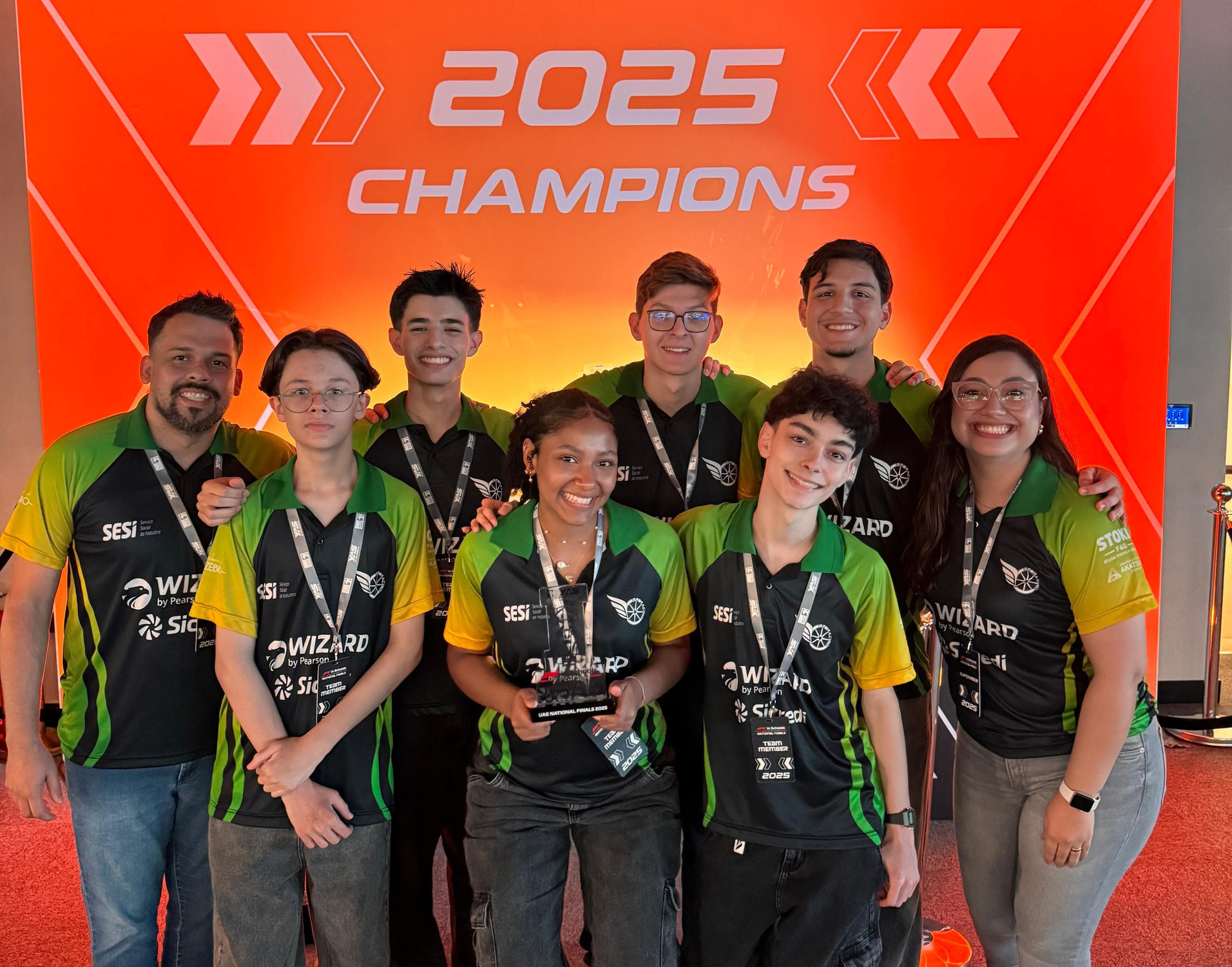 Grupo comemora o título com os professores no painel dos campeões de 2025, marcando a vitória brasileira nos Emirados Árabes.