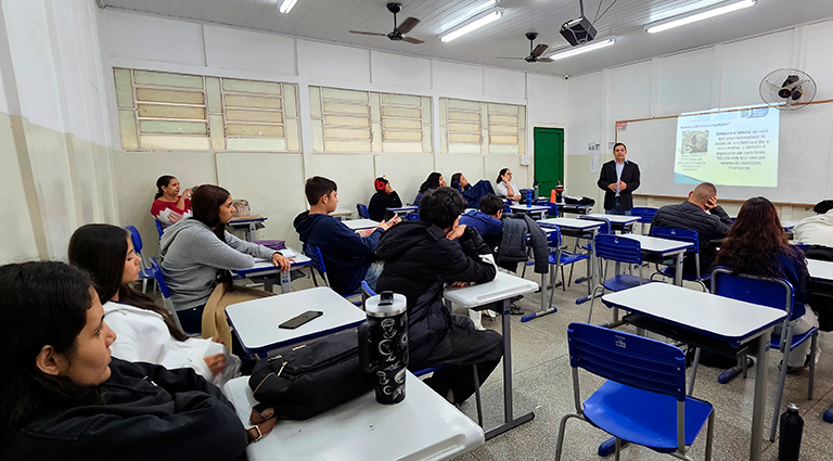 Professor conversa com turma da Escola Estadual Aracy Eudociak, onde o projeto ensina os jovens a planejarem melhor seus gastos e evitarem dívidas.