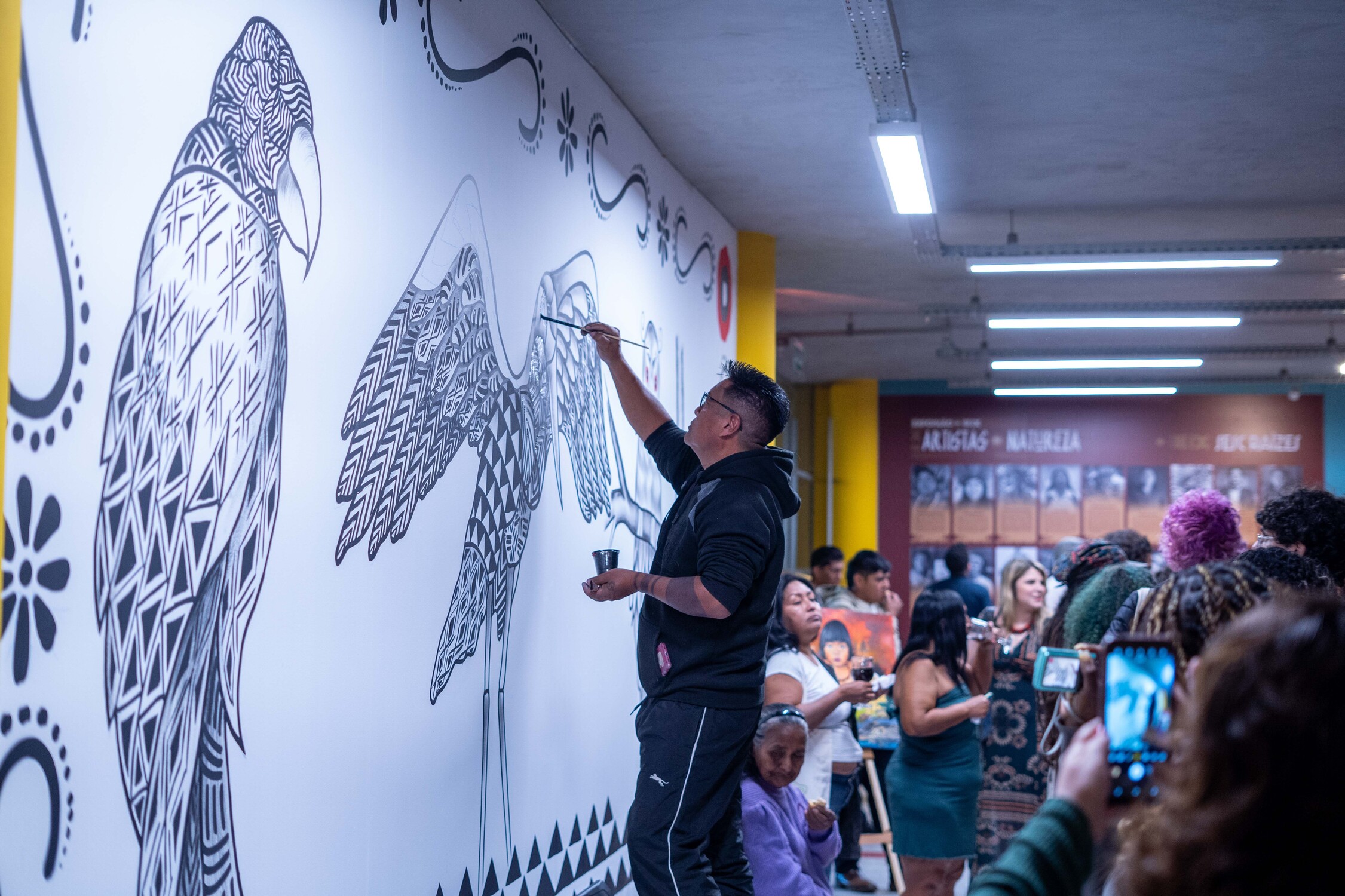 Obra em pintura mural sendo criada durante a exposição, com interação do público