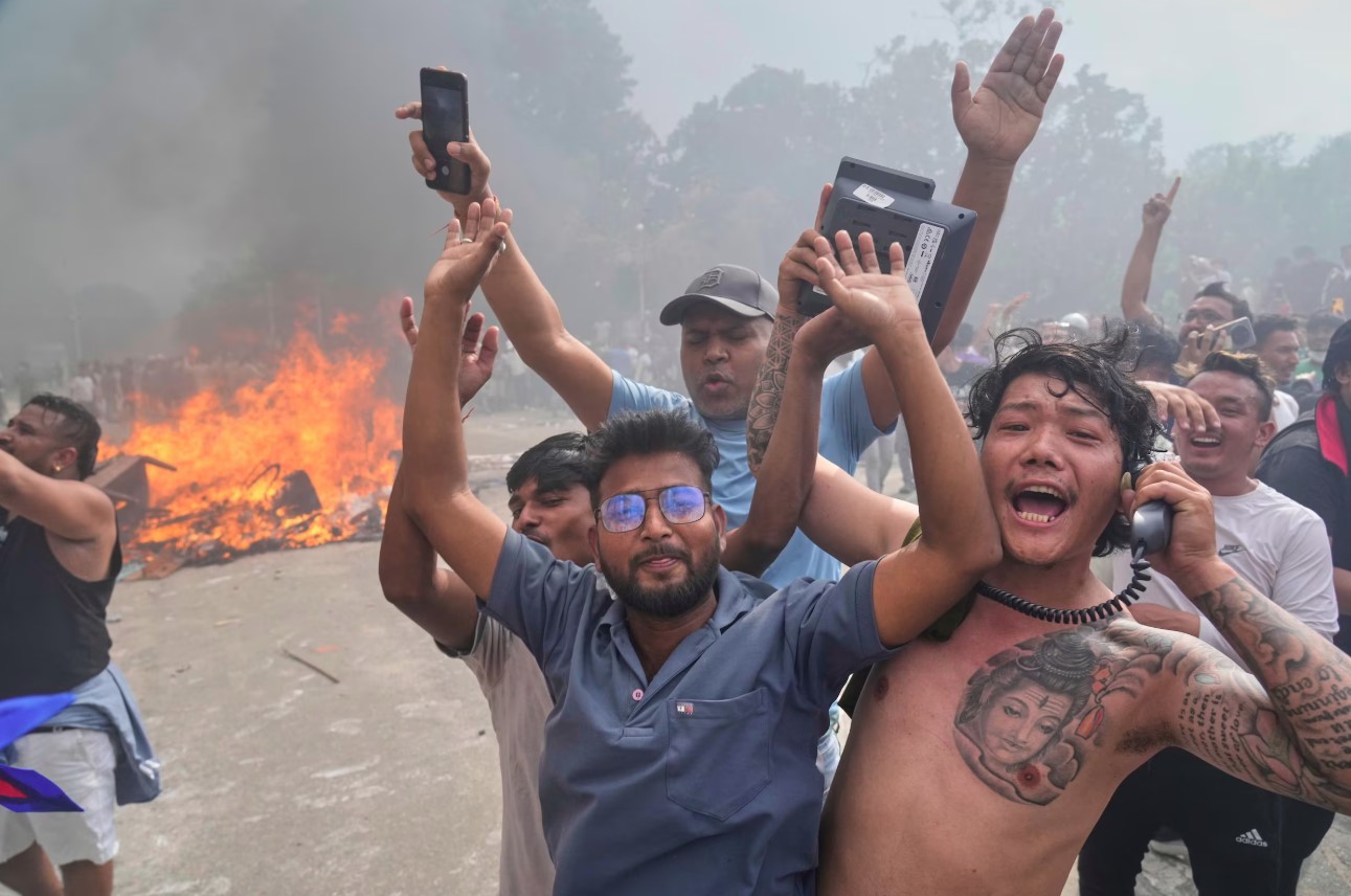 Manifestantes comemoram no Singha Durbar, sede de vários ministérios e escritórios do governo do Nepal, após incendiá-lo durante um protesto contra a proibição de mídias sociais e corrupção em Katmandu