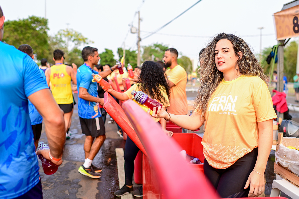 Voluntários distribuem isotônicos aos atletas durante o percurso da Corrida do Pantanal