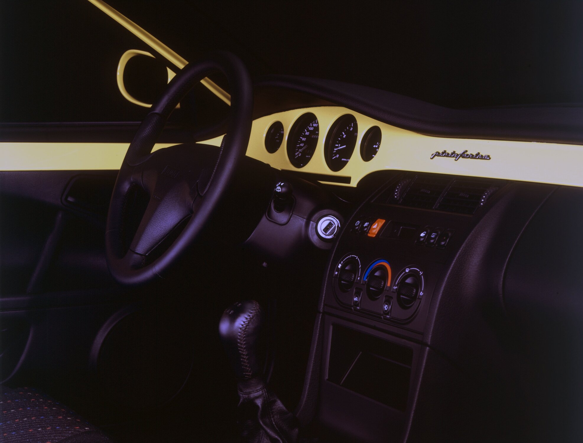 Interior do Fiat Coupé traz painel com faixa colorida e assinatura Pininfarina, reforçando o DNA italiano do modelo.