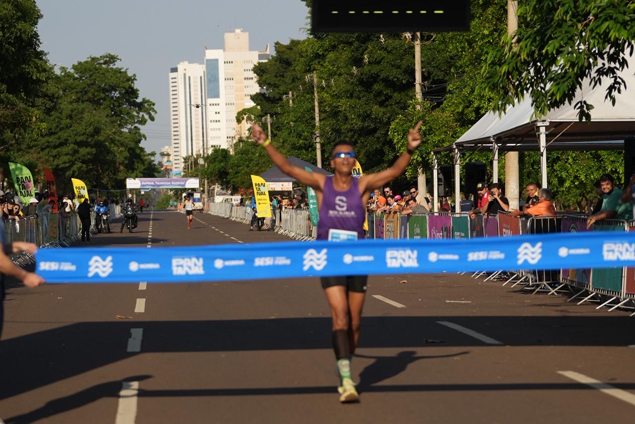 Eduardo Janô cruza a linha de chegada em primeiro lugar na categoria geral dos 10 km, celebrando a vitória com os braços erguidos.