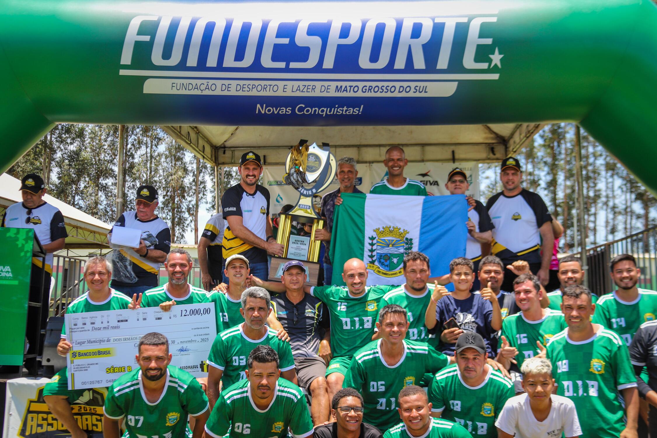 Time de Dois Irmãos do Buriti comemora o título da Série B da Copa Assomasul 2025 com o troféu e o cheque de R$ 12 mil em Nova Andradina.