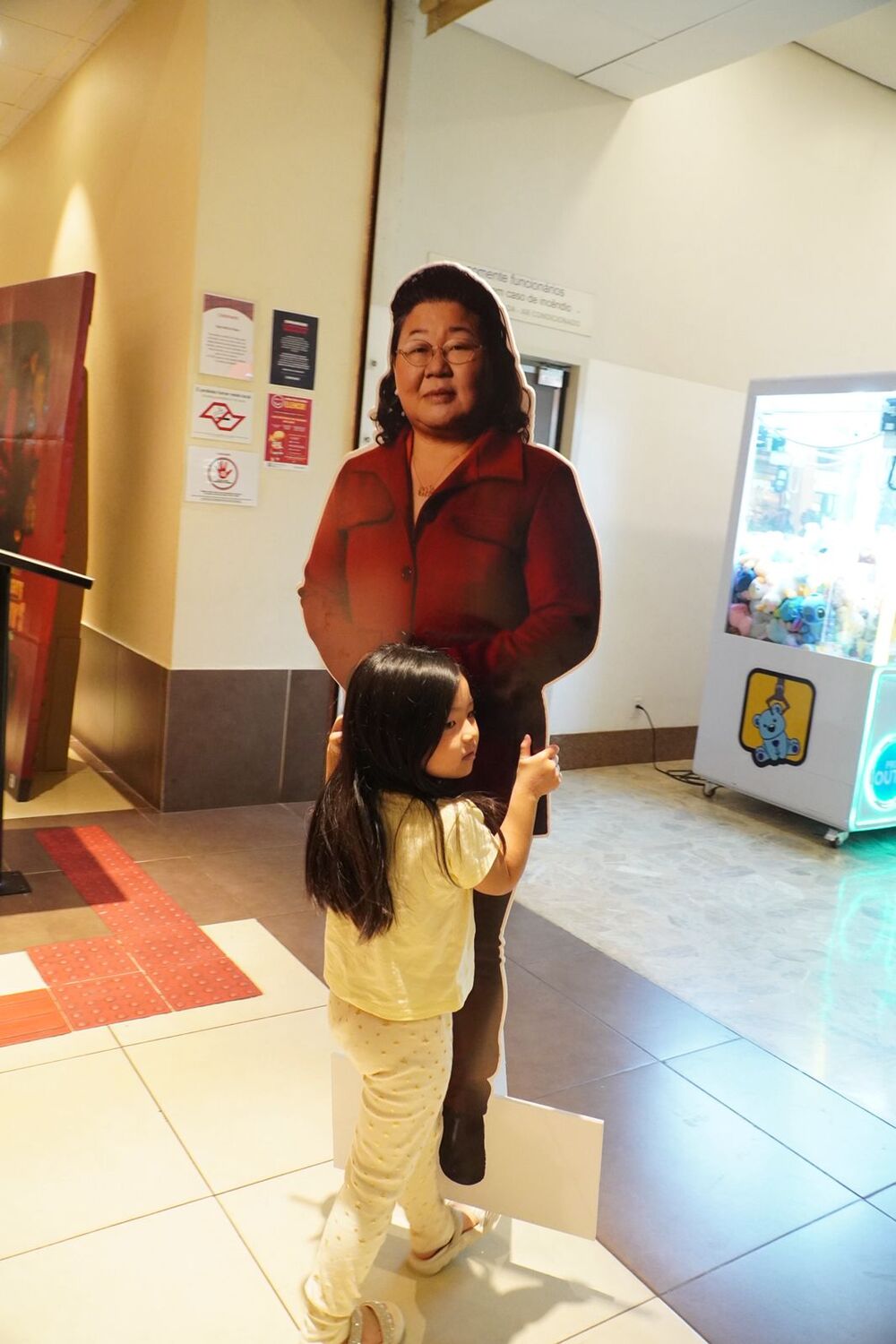 Criança interage com totem de uma das protagonistas de Mulheres da Fronteira no hall do Cinemark, em Campo Grande.