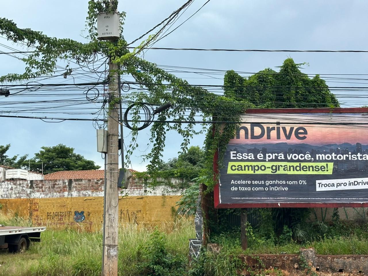 Fios de telefonia e internet pendurados em poste de Campo Grande seguem oferecendo risco a quem passa, mesmo após lei que obriga retirada de cabos inativos.