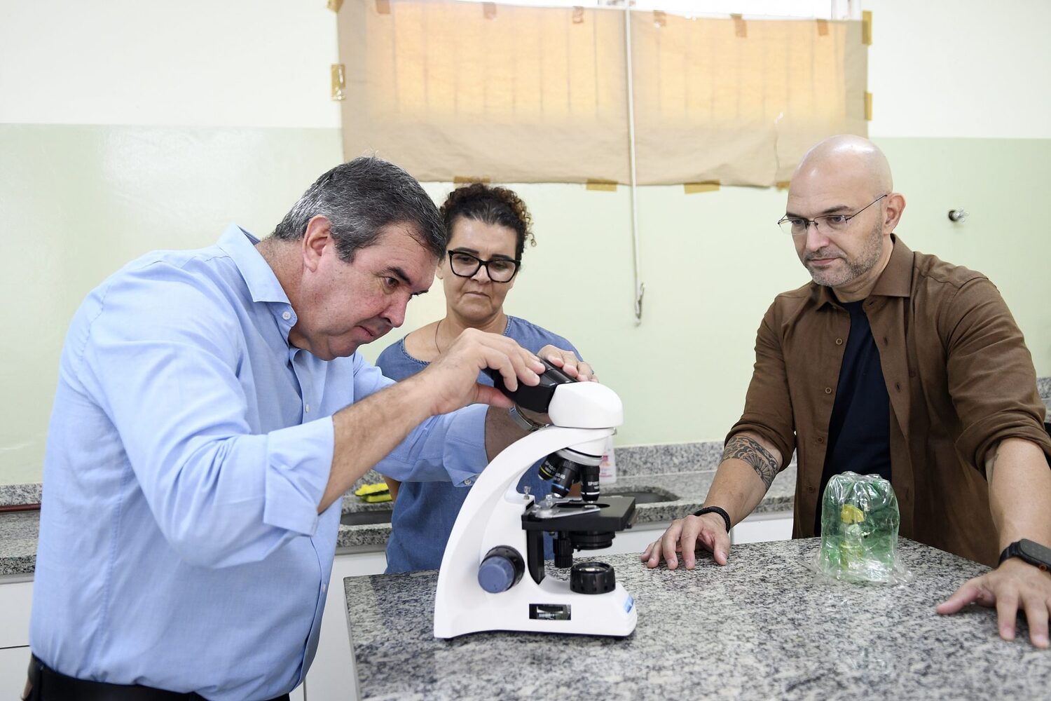 Eduardo Riedel observa o microscópio no laboratório da rede estadual