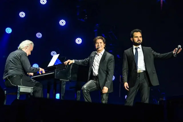 João Carlos Martins toca piano durante a música 'Fio de Cabelo' ao lado de Xororó e Luciano no show 'Amigos - 20 Anos'. 